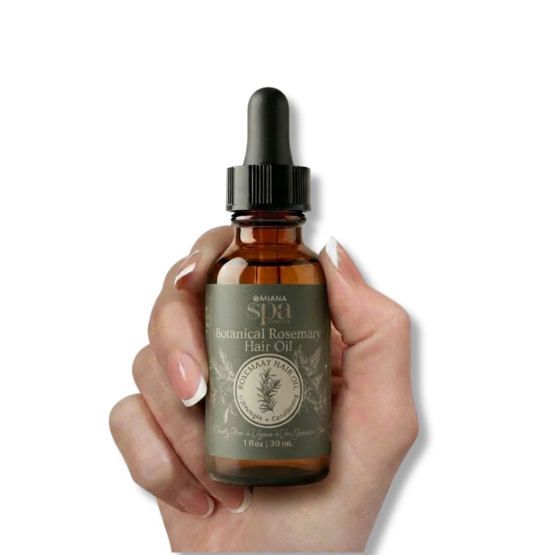Hand holding a bottle of Omiana Spa Botanical Rosemary Hair Oil against a white background