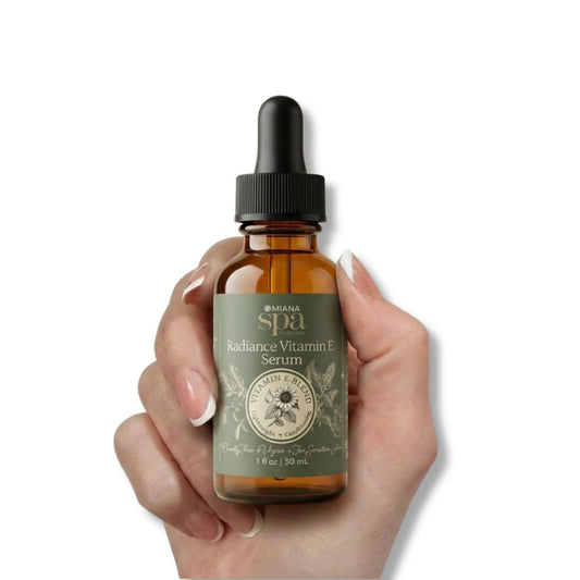 Hand holding a bottle of Omiana Spa Radiance Vitamin E Serum on a white background